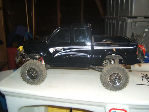 1988 Ford Bronco - A black RC Ford F-350 pickup truck with off-road tires is shown in profile, resting on a white surface.