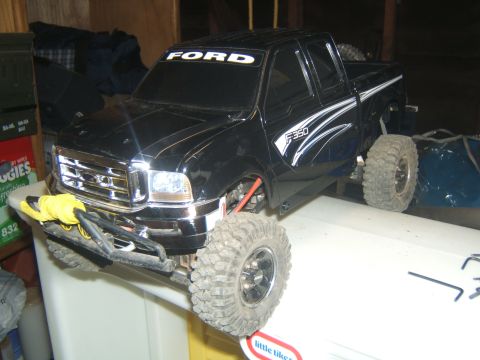 1988 Ford Bronco - A black remote-controlled Ford F-350 pickup truck is shown from a 3/4 front angle, resting on a white surface. The truck features large off…