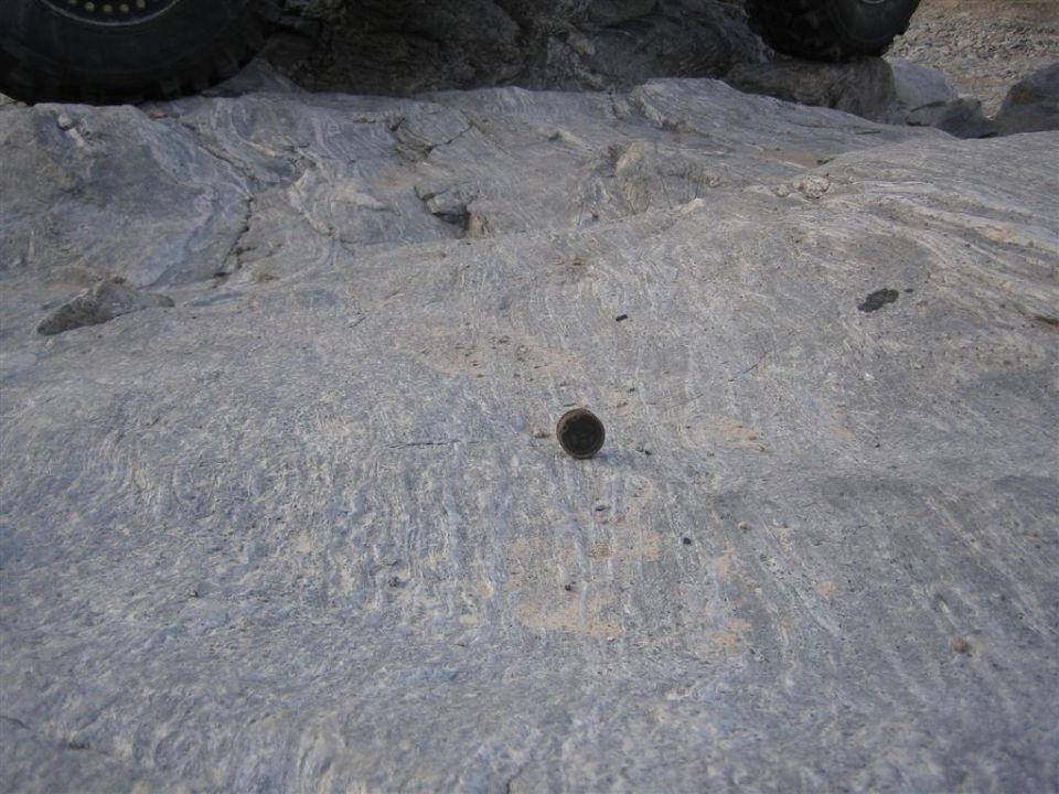 Tire and rocky ground with a small metal object.