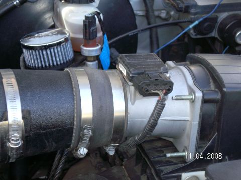 1996 Ford Bronco - A close-up view of the engine bay of a 1996 Ford Bronco, focusing on the air intake system and associated sensors. Visible parts include a…
