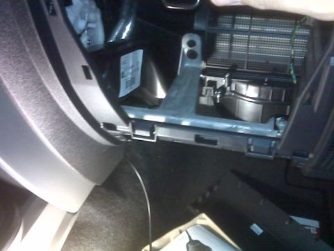 2008 Jeep Wrangler - The image shows the interior of a vehicle, likely the passenger side footwell, with the cabin air filter housing and blower motor exposed.…