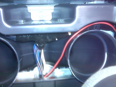 2008 Jeep Wrangler - A bundle of multi-colored wires is visible, connected to a red wire, emerging from behind black tape. Two dark circular openings, likely ai…