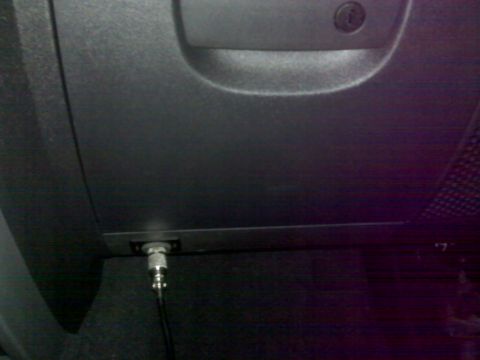 2008 Jeep Wrangler - A close-up view of a coaxial cable connector plugged into a port on the back of a dark-colored vehicle. The connector is silver and black,…