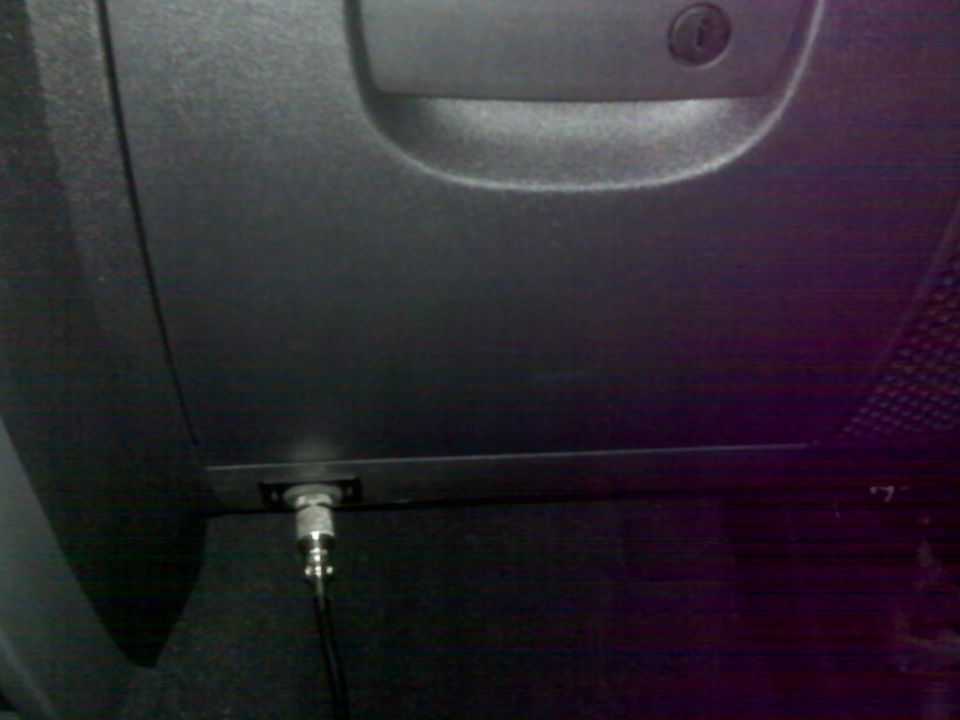 Coaxial cable connector plugged into a port on a dark vehicle.