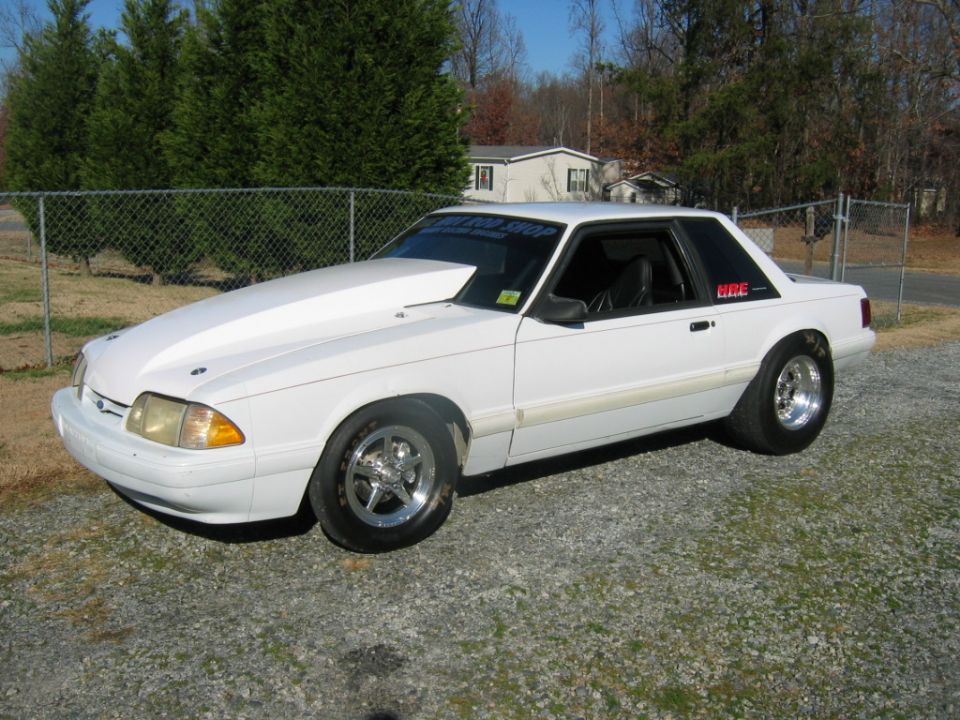 White 1992 Ford Mustang coupe with cowl hood and drag wheels.