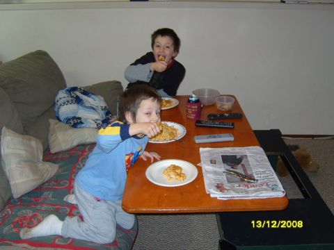 1989 Ford Bronco - Two young boys are eating at a table. The boy in the foreground is wearing a blue shirt and grey pants, and is looking at the camera while…