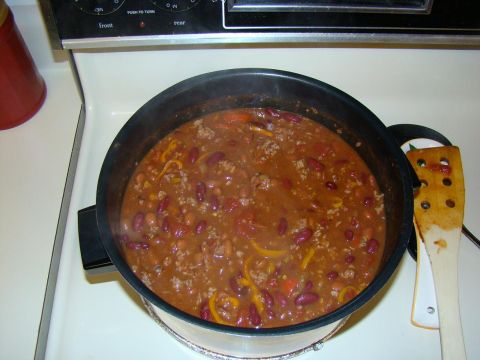 1989 Ford Bronco - A pot of chili is simmering on a white electric stovetop. A wooden spoon rests on the side of the pot.