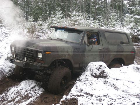 1989 Ford Bronco - A camouflage-painted Ford Bronco is stuck in the mud and snow, with steam or smoke coming from the front of the vehicle. The vehicle is in…
