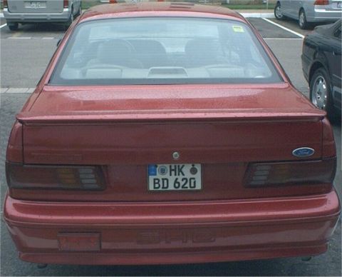 1991 Ford Taurus - German-style SHO: Rain, US Army Europe plates, aftermarket rear foglight, and ADAC (German AAA) sticker in the top right back window.