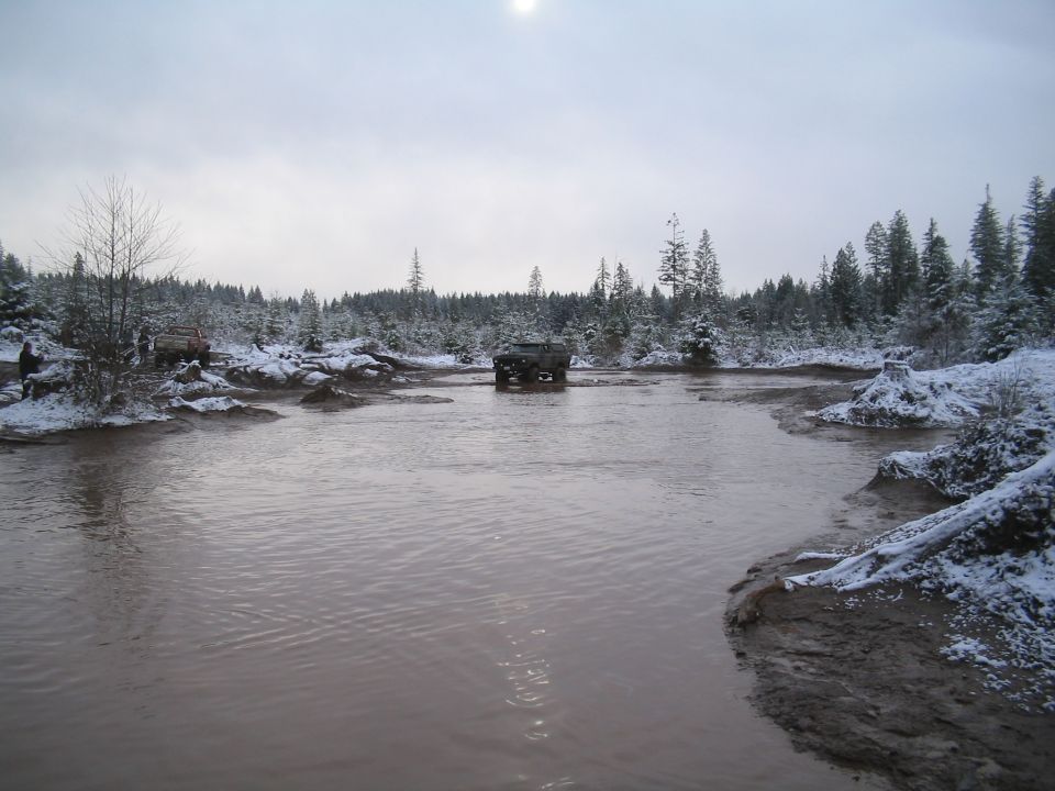 Off-road vehicles in a muddy, snowy forest.