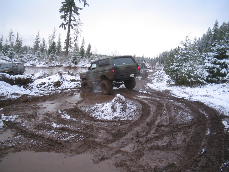Camouflage Ford Bronco driving through mud and snow.