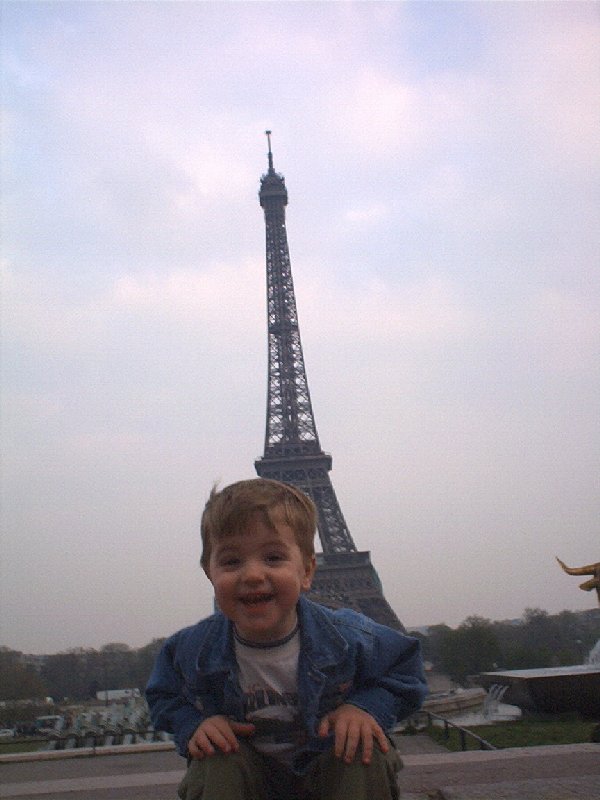 Smiling child in denim jacket in front of the Eiffel Tower in Paris