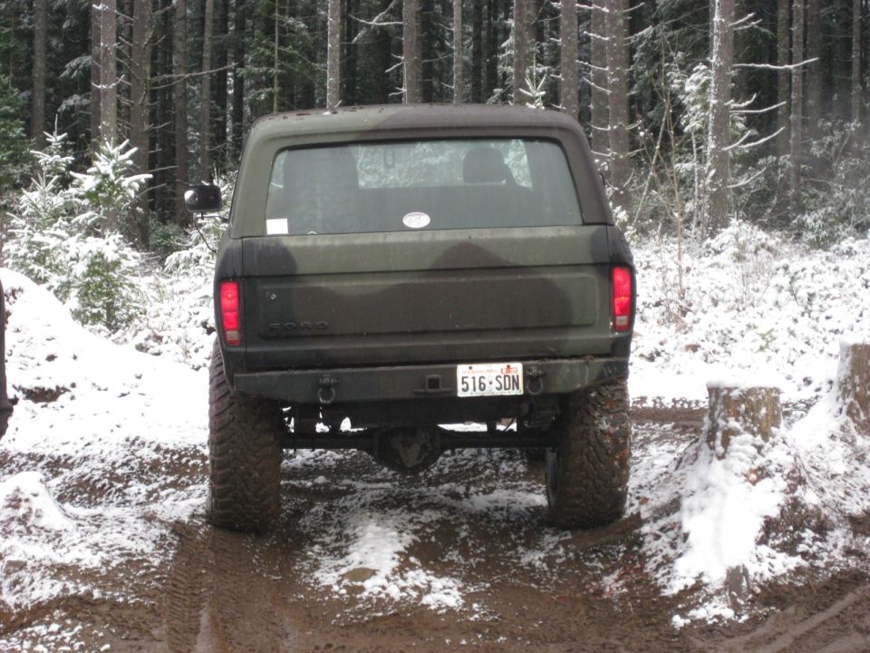 Rear view of a camouflaged Ford Bronco in a snowy forest.