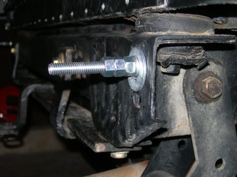 1991 Jeep Wrangler - A close-up view shows a threaded bolt with nuts and washers securing a black metal bracket to a vehicle's frame. The bolt appears to be par…