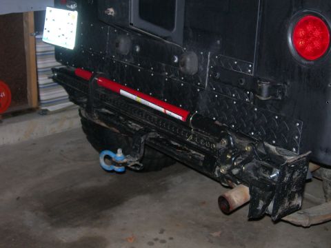 1991 Jeep Wrangler - The rear of a black Jeep Wrangler is shown with a Hi-Lift jack mounted horizontally to the rear bumper. A blue tow shackle is attached to t…