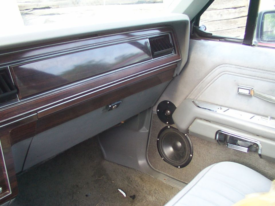 Passenger-side interior with woodgrain dash and aftermarket tweeter and woofer mounted in gray kick panel