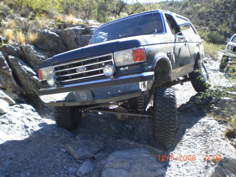 1991 Ford Bronco - Ford Bronco navigating a challenging rocky off-road path.