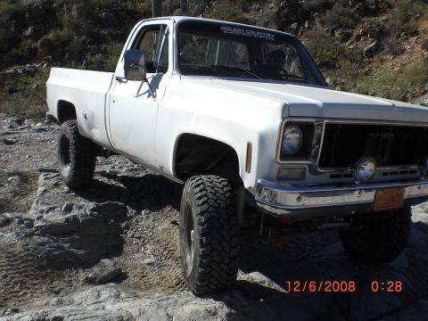 1991 Ford Bronco - White pickup truck with off-road tires navigating rocky terrain.