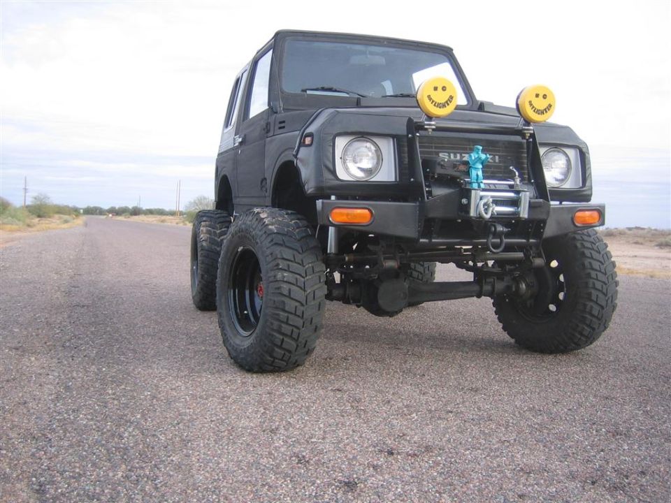 Lifted black Suzuki Samurai hardtop on desert road with winch bumper and KC lights