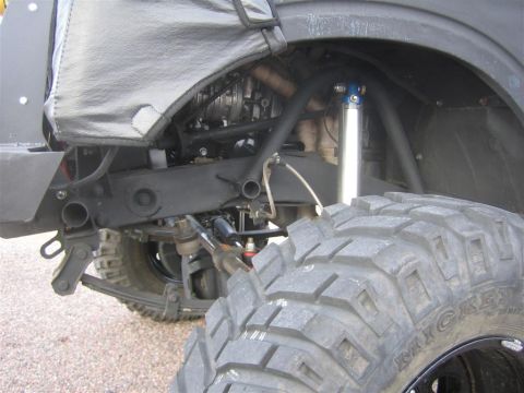 1987 Suzuki Samurai - Close-up view of the suspension system and large tire of an off-road vehicle.