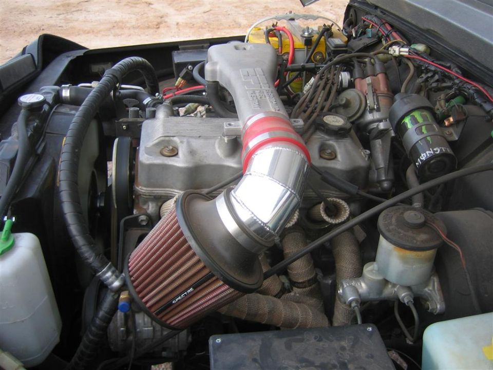 1987 Suzuki Samurai engine bay with aftermarket air intake and exhaust manifold wrap
