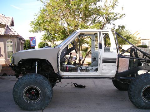 1986 Toyota Hilux - This heavily modified 1986 Toyota Hilux pickup truck features oversized tires and a stripped-down interior, suggesting a custom off-road bu…