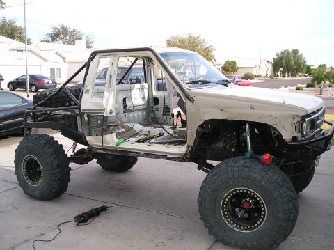 1986 Toyota Hilux - This heavily modified pickup truck is undergoing a custom build, oversized tires and a stripped-down interior.