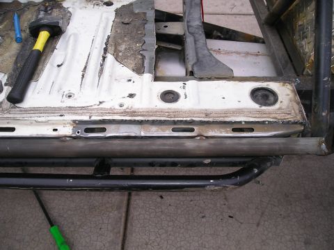 1986 Toyota Hilux - Close-up view of a heavily modified truck frame, a roll cage and running boards, with visible rust and evidence of repairs.