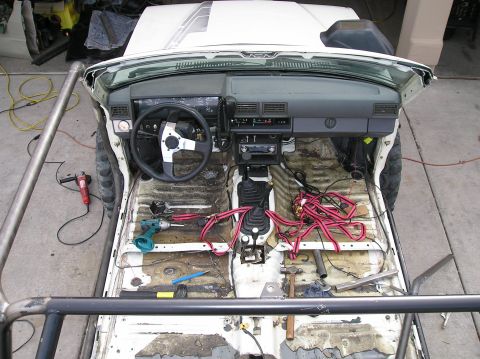 1986 Toyota Hilux - The interior of a 1986 Toyota Hilux is shown stripped down, revealing the floor and scattered tools, indicating ongoing work.