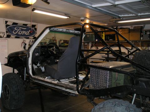 1986 Toyota Hilux - Custom roll cage installed in an off-road vehicle's interior, with a Ford flag on the wall.