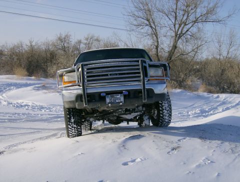2000 Ford F-250 - A 2000 Ford F-250 navigates a snowy terrain, equipped with a prominent brush guard for off-road protection.