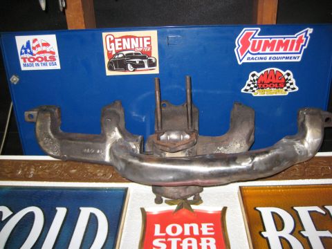 1953 Ford Mainline - A close-up of an exhaust manifold is displayed in front of a blue toolbox adorned with racing and tools stickers.