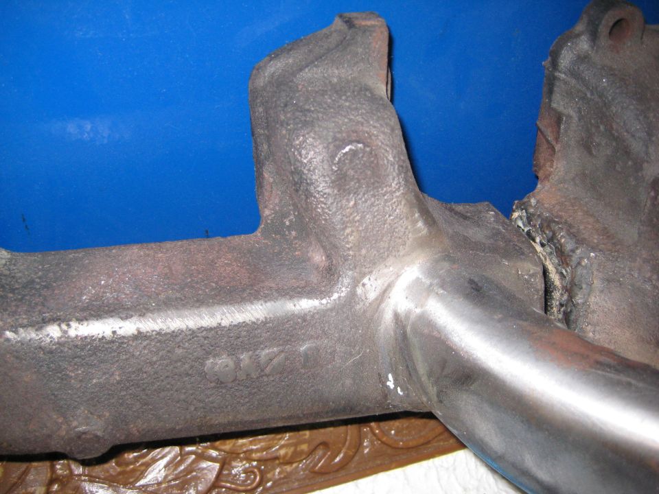 Cast iron exhaust manifold with visible casting marks and a broken section