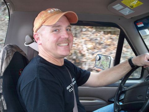 1996 Ford Bronco - Man driving a truck on a wooded road.