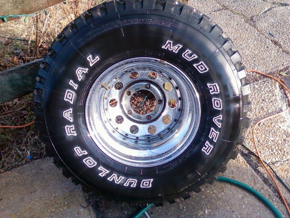 Close-up of a Dunlop Mud Rover radial tire with white lettering on a chrome rim.