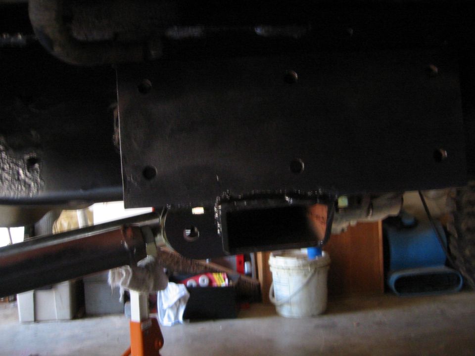 Black fabricated crossmember and skid plate bolted between truck frame rails from below