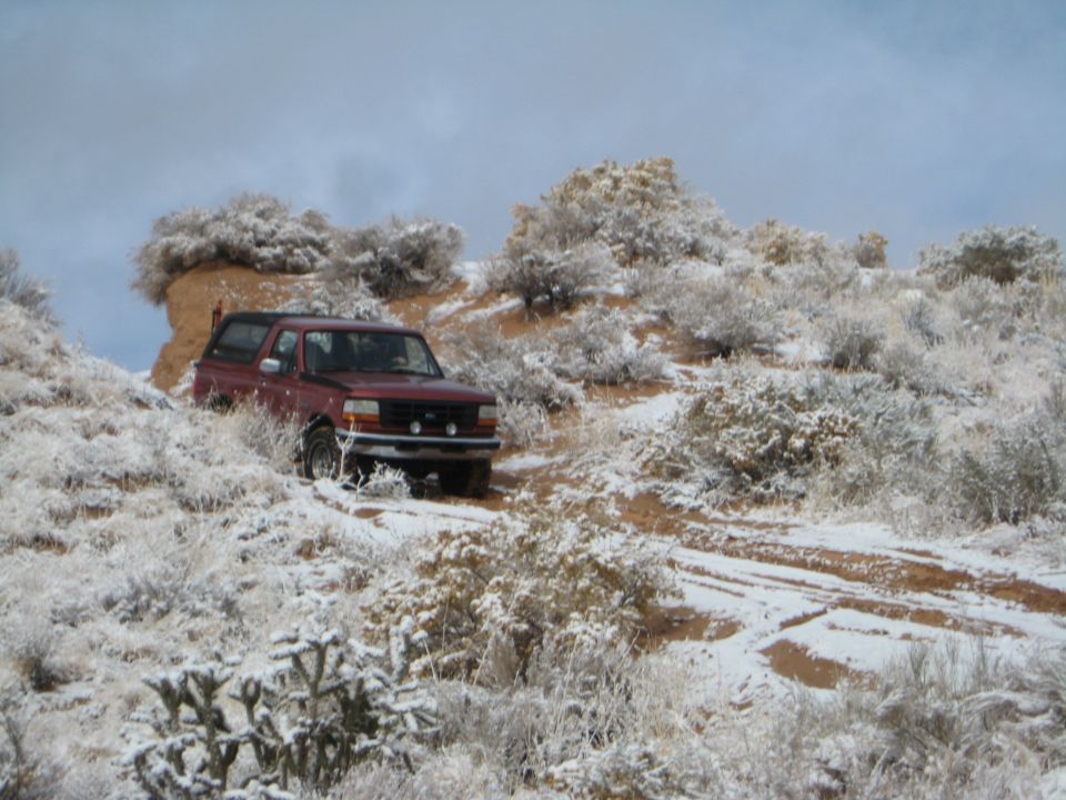 Red Ford Bronco on a snowy desert trail.