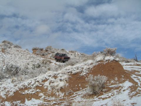 1993 Ford Bronco - A red 1993 Ford Bronco navigates a snowy mountain landscape.