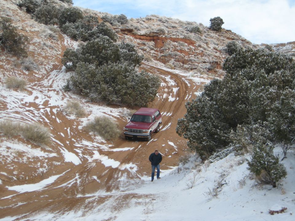 Red 1993 Ford Bronco on a snowy dirt road.