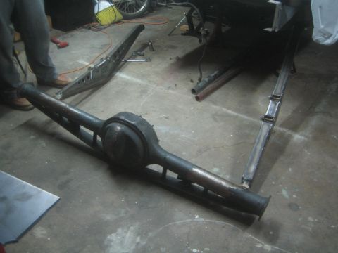 1990 Ford Bronco - Photograph of a fabricated axle housing and suspension links on a shop floor, not a document.