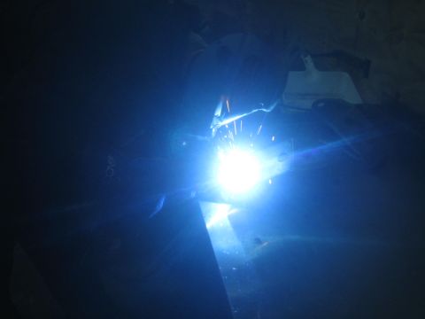 1990 Ford Bronco - Photograph of a bright welding arc on steel in a dark shop, not a technical document.