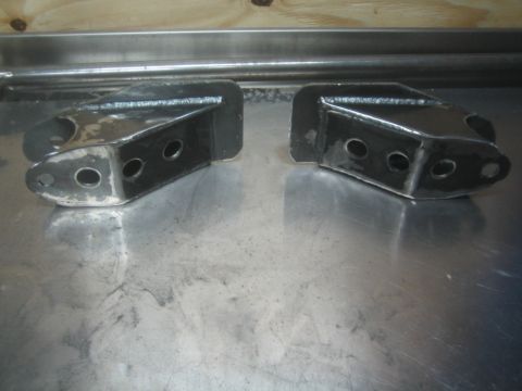 1990 Ford Bronco - Photograph of a pair of fabricated steel suspension brackets, not a technical document.