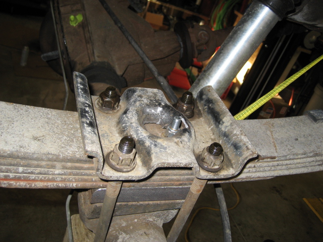 Close-up of rusty U-bolt and leaf spring hardware on a vehicle underside.