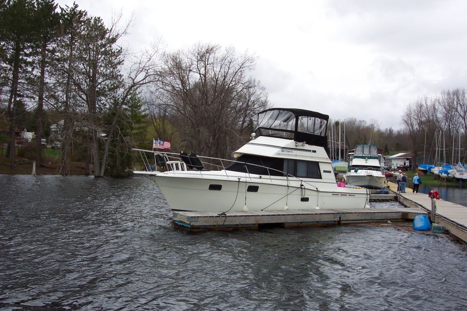 White cabin cruiser boat with flybridge docked at a lake marina