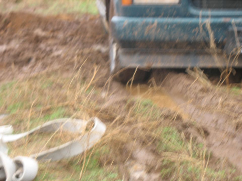 Vehicle stuck in mud with a white hose.