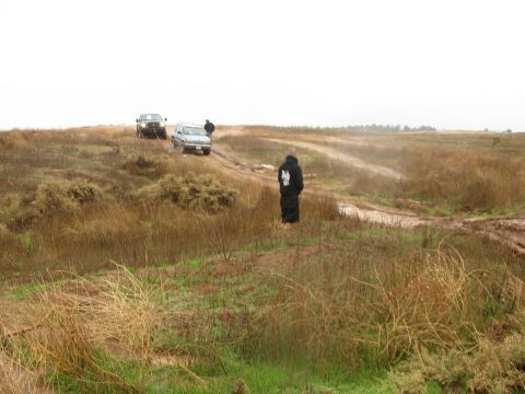 2001 Ford F-250 - Two vehicles are stuck in the mud on a dirt road in a grassy, overgrown field under a cloudy sky. One vehicle is a light-colored SUV, and t…