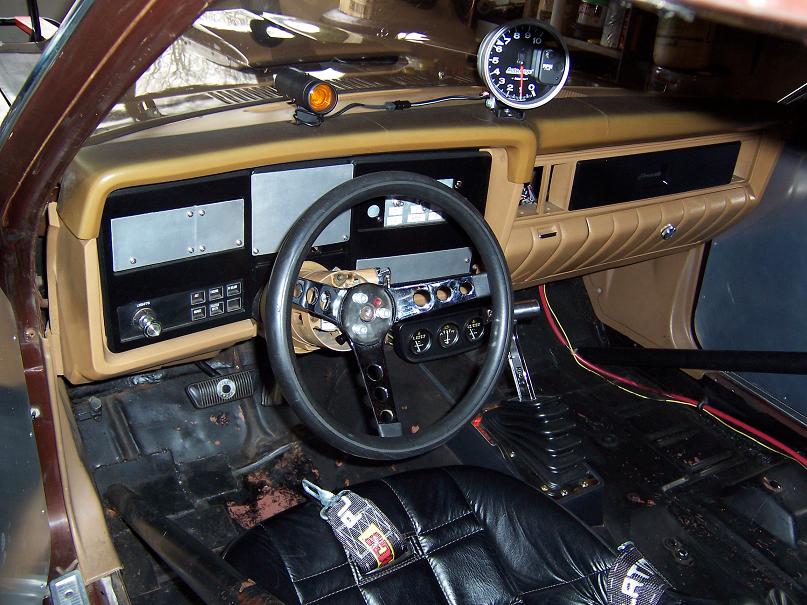 Interior of a classic car with custom steering wheel, gauges, and racing seats.