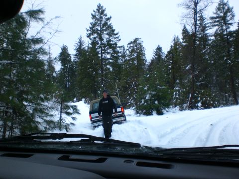 1995 Ford Bronco - A man stands next to a pickup truck in a snowy forest. The truck appears to be a Ford Bronco, possibly a 1995 model, with its tires deep in…