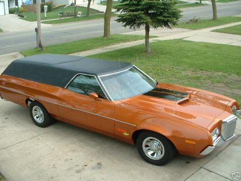1972 Ford Ranchero - A shiny orange 1972 Ford Ranchero with a black vinyl top is parked on a concrete driveway. The vehicle has black racing stripes on the hood…