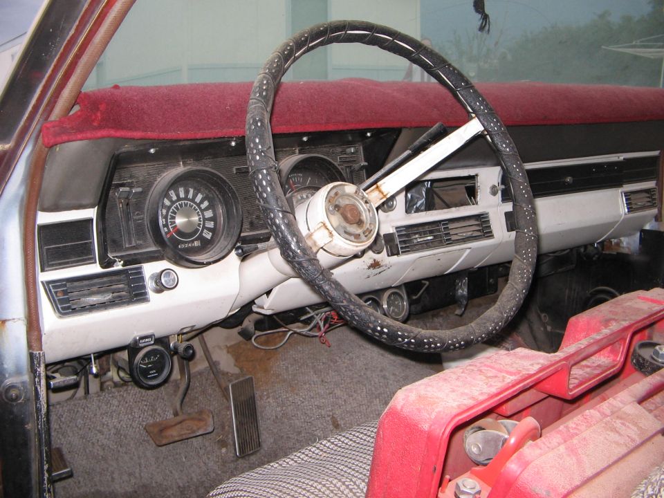 Bare interior of a 1966 Ford Ranchero showing white dash, gauges, wrapped steering wheel and red dash pad, seats removed.